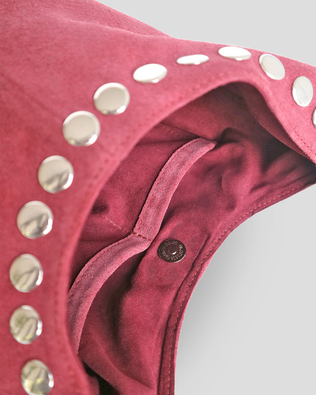 Close-up of a pink leather product with silver studs on a white background