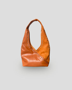 Orange mariposa leather handbag with studs on a light gray background