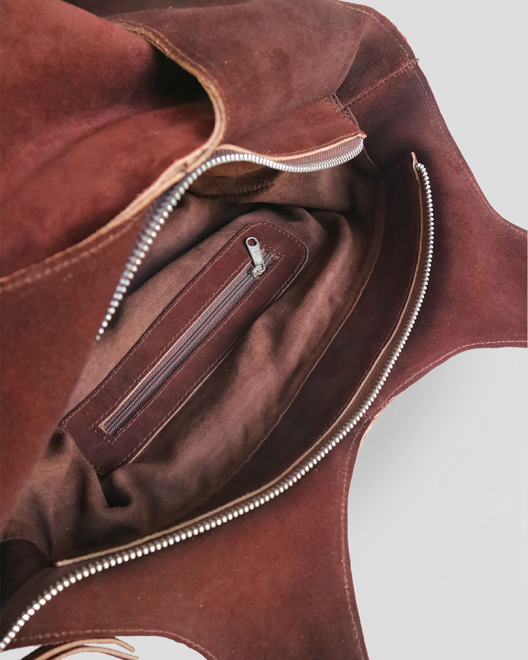 Close-up of a brown suede leather bag with zippers.