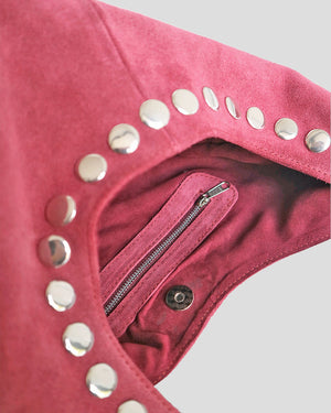 Close-up of a pink garment with silver studs and a zipper on a light gray background