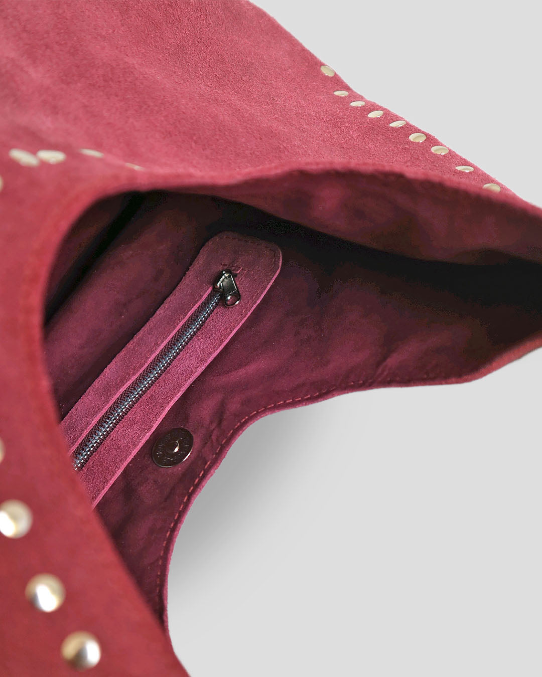 Close-up of a navya suede shoulder bag with a zipper detail.